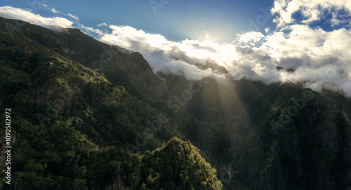 Levada in the mountains of Madeira, with the sun and some clouds in the sky, a summer day
