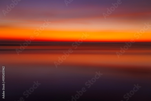 Fototapeta Naklejka Na Ścianę i Meble -  Long exposure abstract fine art photography of a red and orange sunset over the ocean. 