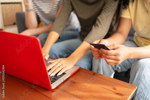 Young women friends buying online on laptop with a credit card at home. Black Friday deals photo