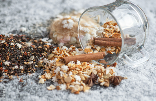 winter hot drink ingredient spiled  with spices, star-shaped and sugar  and  glass  cup turn over on  snowy background photo