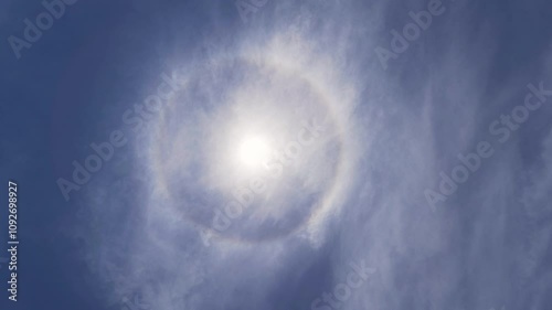 Low angle shot of solar halo, a complete circular rainbow around the sun in blue sky