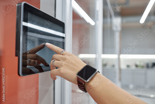 Close up on hand of woman wearing set of elegant silver rings unlocking office door using touch screen on wall, modern security system concept, copy space