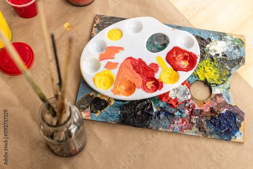 Colorful paint palette and brushes on table, ready for creative art project, at home photo