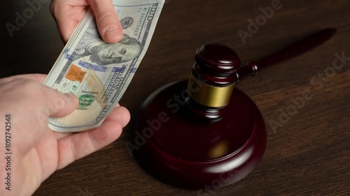 Justice and money, corruption and bribery concept. Close-up hand giving bribe money to Lawyer with Judge gavel on table