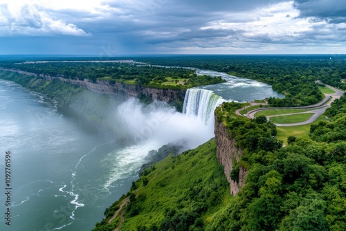 Aerial view of a massive waterfall plunging into a lush green canyon, with mist rising from the falls