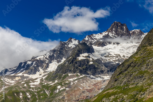 Val Veny scenic landscape in Courmayeur valley, Italy on Tour du Mont Blanc hiking route. Alps beautiful landscape, scenic view of the alpine peaks, green fields and meadow with flowers and blue sky photo