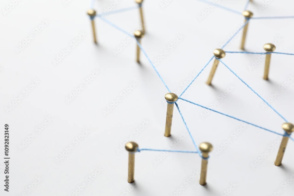 Obraz premium Network connection. Nails linked together by thread on white table, closeup. Space for text