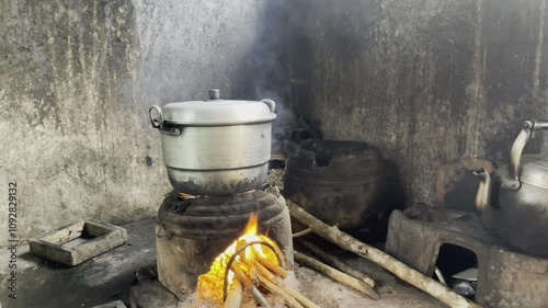 Footage of cooking water using aluminum kettles and wood charcoal fuel. Black aluminum kettle. Smoke partially covers the kettle