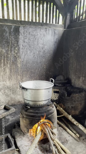 Footage of cooking water using aluminum kettles and wood charcoal fuel. Black aluminum kettle. Smoke partially covers the kettle