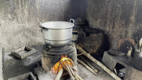 Footage of cooking water using aluminum kettles and wood charcoal fuel. Black aluminum kettle. Smoke partially covers the kettle