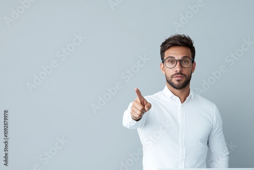 A man wearing glasses points forward with confidence in a bright, well-lit space, symbolizing leadership, decision-making, and modern professionalism. photo