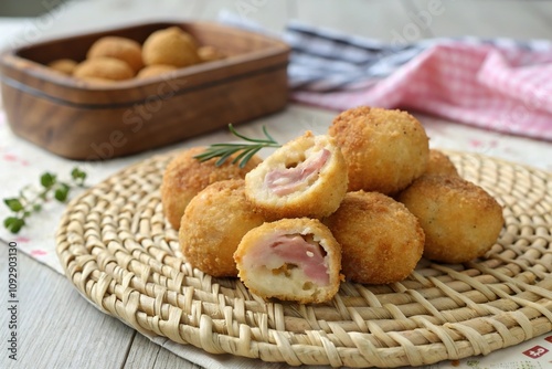 A cluster of ham and cheese-filled croquettes on a woven placemat, golden, restaurant