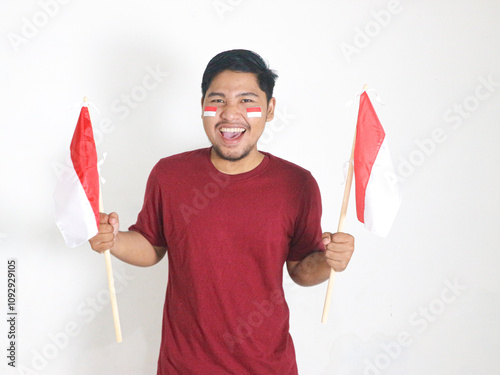 Excited young Asian men celebrate Indonesian independence day on 17 August by holding the Indonesian flag isolated over white background photo