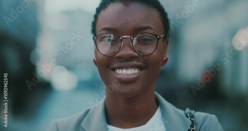 Attractive smiling stylish African American woman with glasses standing near business centre. Look at camera. At sunlight. Face, beautiful, close up, street, businesswoman, confidence. Slow motion