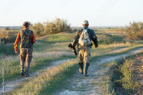 Mature hunter man holding a shotgun and walking through a field photo