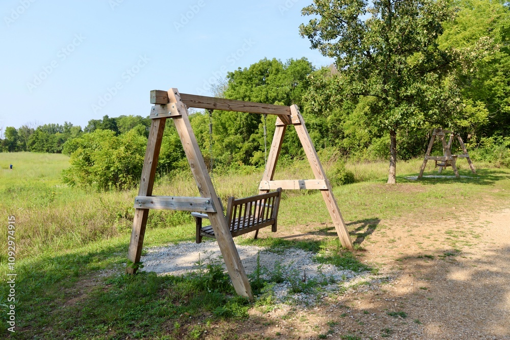 The old wood swinging bench in the park on a sunny day. The old wood swinging bench in the park on a sunny day.