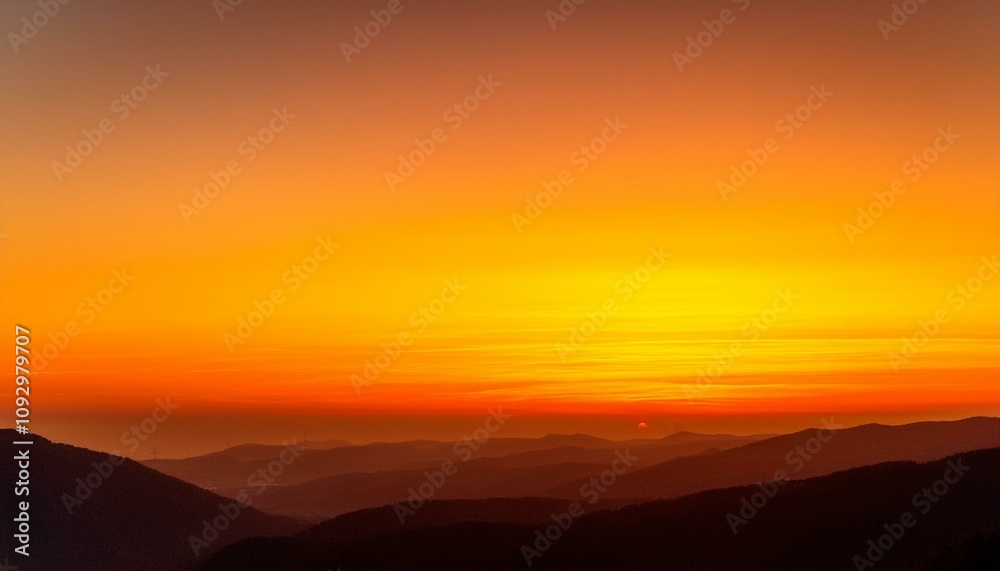 Fiery sunset over a mountain range. Vivid oranges and yellows paint the sky. Fiery sunset over a mountain range. Vivid oranges and yellows paint the sky.