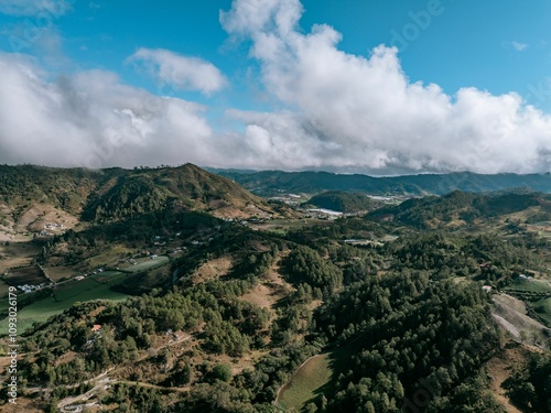 Aerial view of lush green hills under a blue sky.