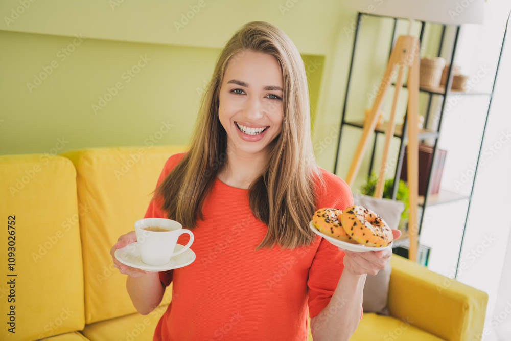Photo of lovely young girl hold coffee donut dressed orange garment spacious house spring indoors room Photo of lovely young girl hold coffee donut dressed orange garment spacious house spring indoors room
