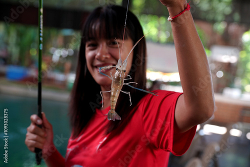 Asian woman stands smiling with shrimp at a shrimp fishing competition in Thailand. photo