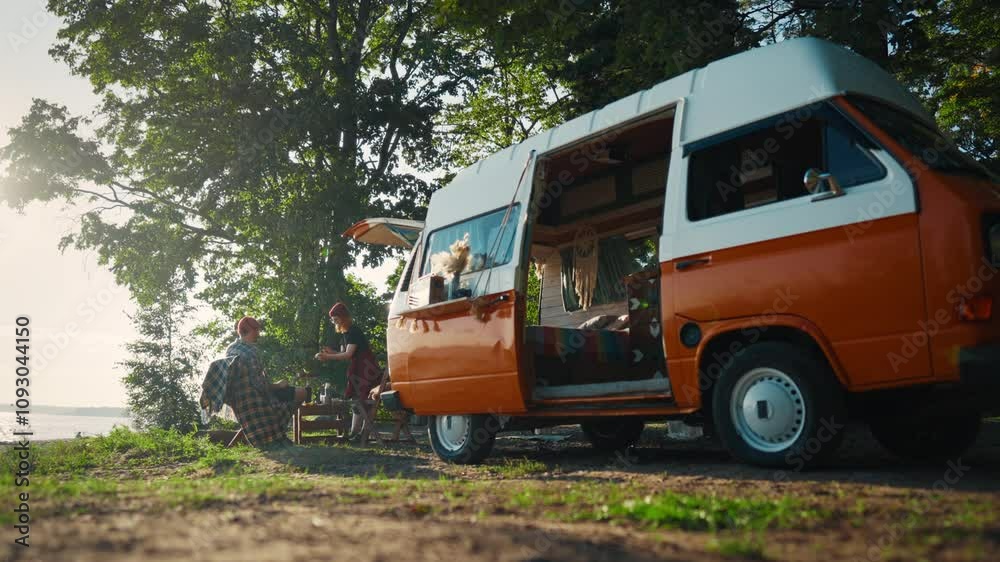 Orange motorhome parked in forest near beautiful river or lake, tourists resting . People traveling by camper in national park in weekend, calm and merry journey in picturesque landscape in summer Orange motorhome parked in forest near beautiful river or lake, tourists resting . People traveling by camper in national park in weekend, calm and merry journey in picturesque landscape in summer