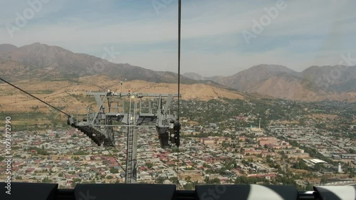 view of the roofs of houses and the Tien Shan mountains from the cable car cabin, Chinorkent, Uzbekistan