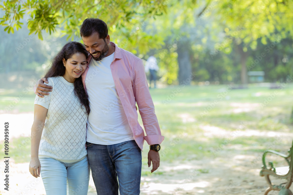 Fototapeta premium Joyful Walk: A Couple Enjoying a Peaceful Moment Together,A candid photograph of a happy couple walking arm in arm through a lush green park.