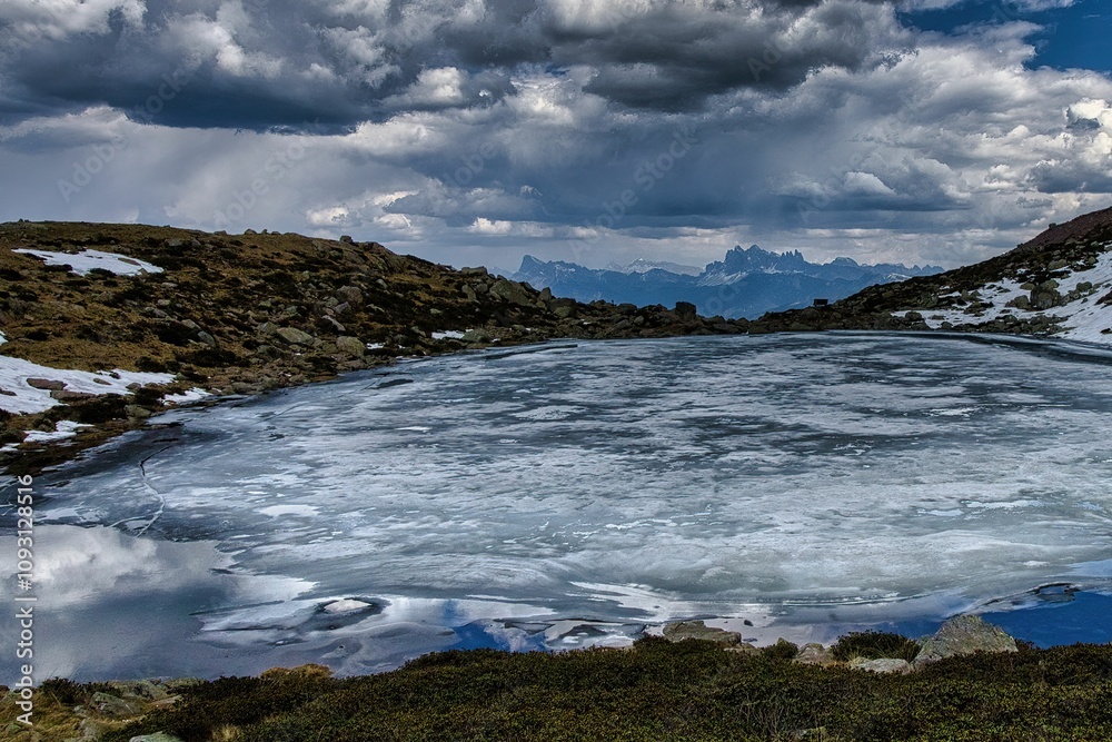 Fototapeta premium Frozen lake with dramatic sky and mountains.