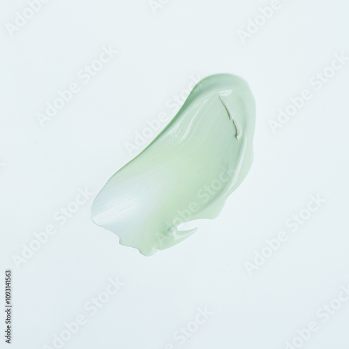 Light green blob of lotion with a soft on a plain white background