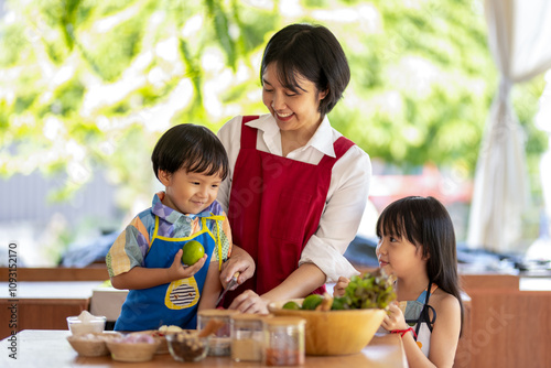 Young asian mother is teaching her two children how to cook a meal