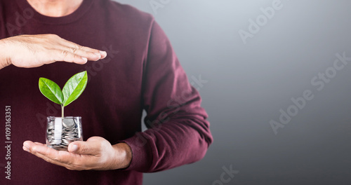 Tableau sur toile Businessman holds a coin jar with a sprouting plant, shielding it with his other hand