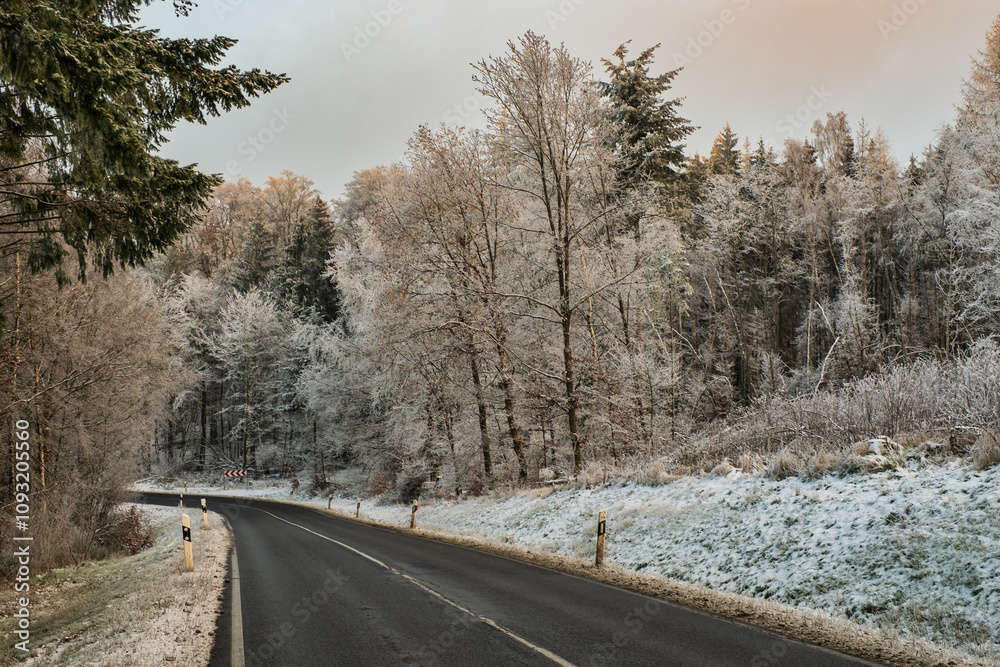 Road in the Taunus through a forest slightly covered in snow Road in the Taunus through a forest slightly covered in snow