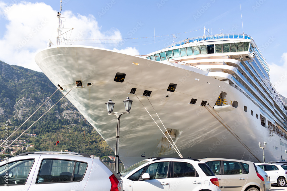 Naklejka premium A large cruise liner docked at the pier against the backdrop of a mountain landscape. Aesthetics of scale.