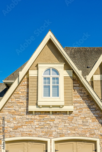 Top of grey stucco luxury house with shingle roof, red and yellow trees and nice windows in Summer in Vancouver, Canada, North America. Day time on June 2024.