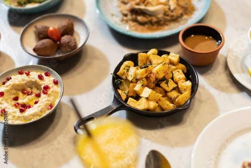 A skillet of crispy batata harra (spicy Lebanese potatoes) sautéed with garlic and garnished with fresh parsley, offering a flavorful and authentic Middle Eastern side dish. photo