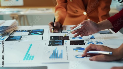 Businesswomen in the office are studying documents with charts and diagrams, working together to develop a business strategy