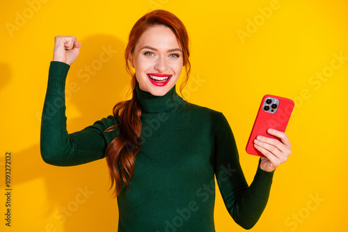 Photo of adorable lucky girl wear green pullover winnin game modern gadget empty space isolated yellow color background photo