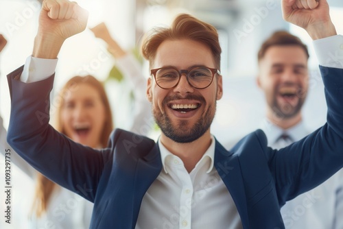 Business team expressing excitement and success with raised arms and joyful smiles, celebrating achievement in a bright office space.