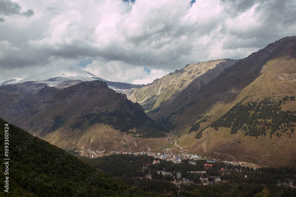 Fototapeta premium Gorgeous sky and rowing hills in the mountains with a small village countryside in the lowland, dark colours