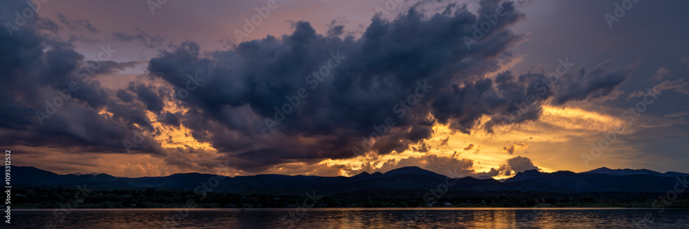 panorama of a dramatic sunset sky and clouds over Rocky Mountains and lake in northern Colorado panorama of a dramatic sunset sky and clouds over Rocky Mountains and lake in northern Colorado