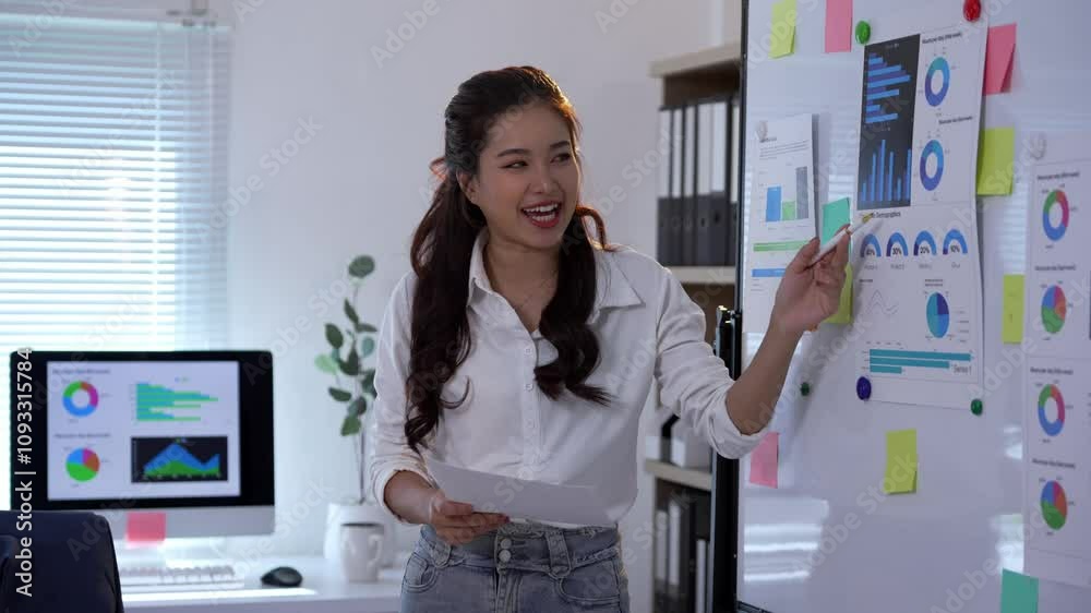 Businesswoman explaining marketing data analysis while pointing at charts on a whiteboard in an office setting Businesswoman explaining marketing data analysis while pointing at charts on a whiteboard in an office setting