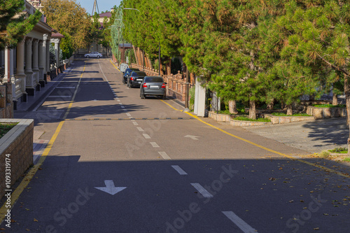 A dead end street in a residential area of the suburbs with a two-lane road, direction arrows, markings with intermittent white and yellow solid stripes. Facades of elite houses with antique columns photo