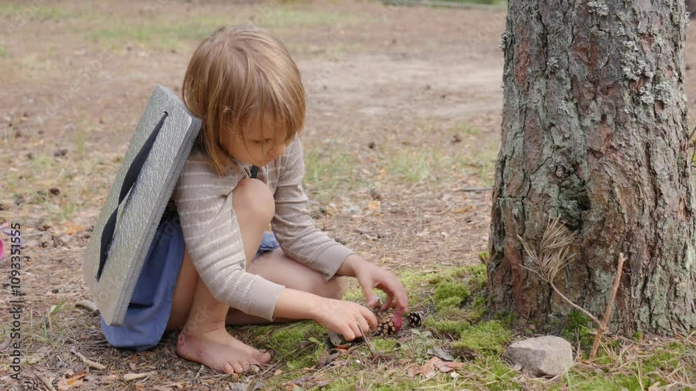 Child playing with pinecones and natural elements in a forest Child playing with pinecones and natural elements in a forest