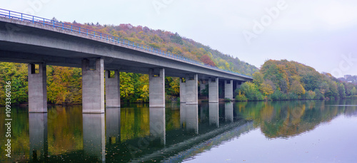 Panoramic photo of a motorway bridge over Lake Seilersee in Iserlohn, Germany. Autumn trees in the background. photo