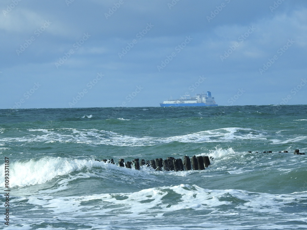 Obraz premium waves crashing on the pier and a cargo vessel