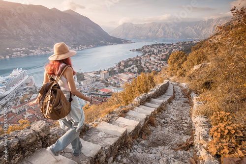 Obraz na płótnie Female tourist descending ancient stone steps, savoring breathtaking view of Kotor bay at sunset in Montenegro w salonie