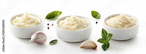 Mélisée garlic sauce in small white bowls, garlic bulbs and leaves on the side, white background,