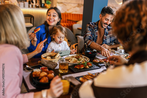 Family and friends gathered in a restaurant to eat delicious food, talk, drink and hang out. photo