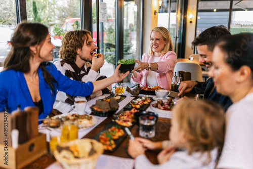 Family and friends gathered in a restaurant to eat delicious food, talk, drink and hang out.