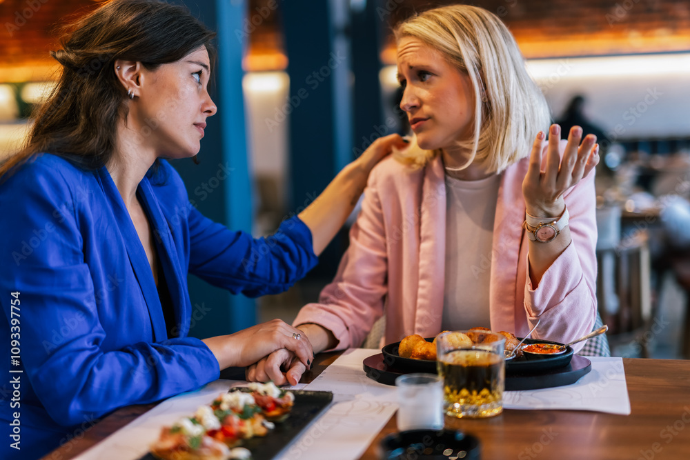 Fototapeta premium Smiling lesbian couple talking to each other at restaurant